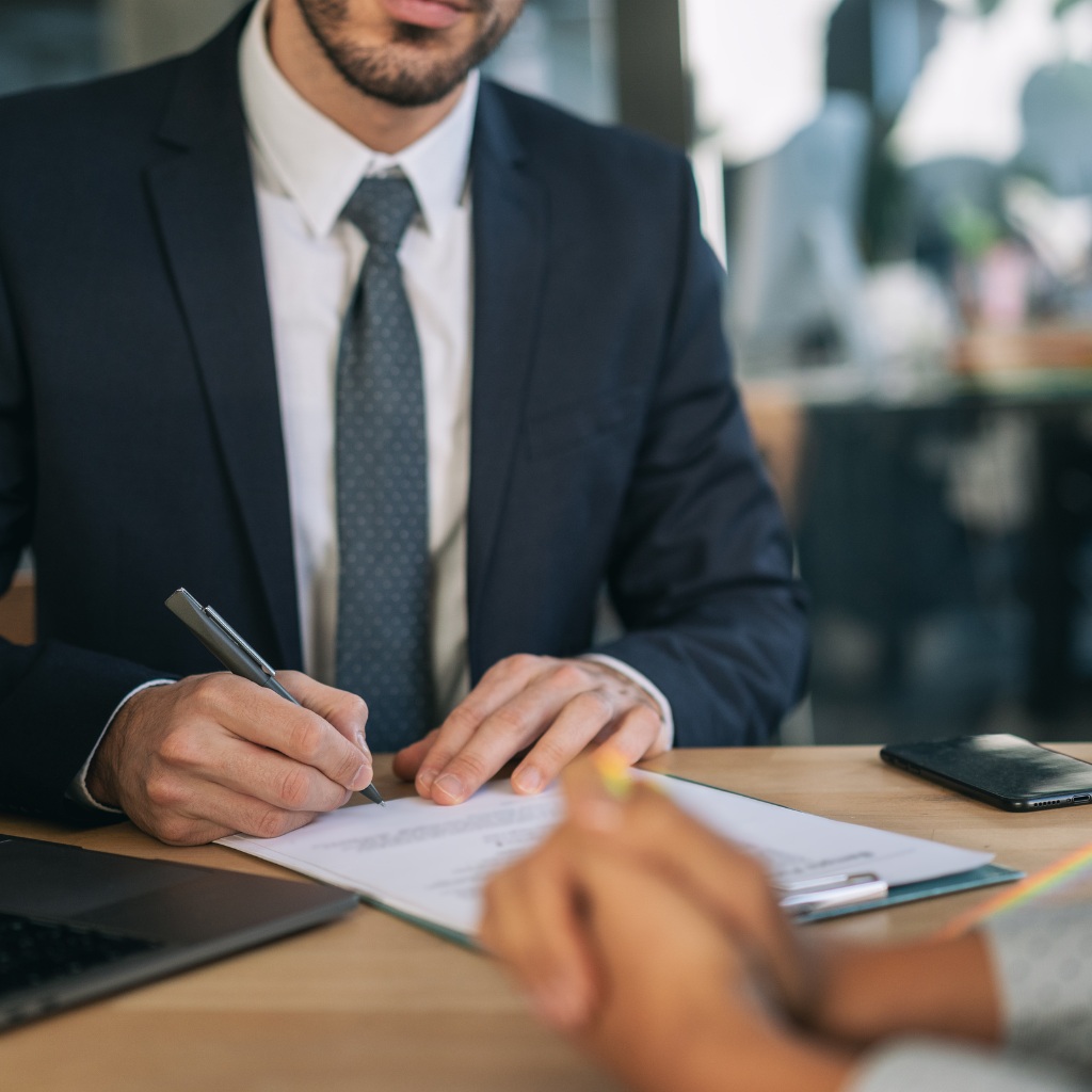 Hombre vestido de traje y corbata firmando contrato